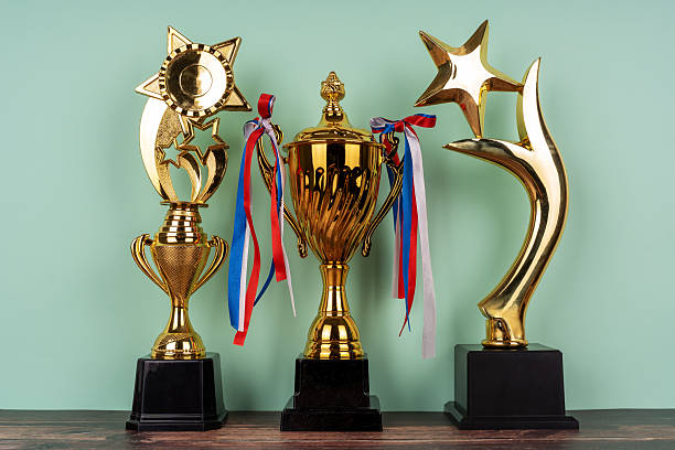 istock Standing golden trophy cups on light green background 2206391715