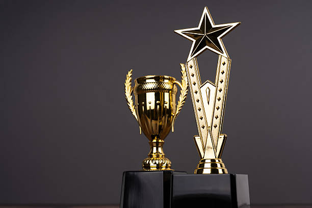 istock Standing golden trophy cups on dark grey background 2206391749