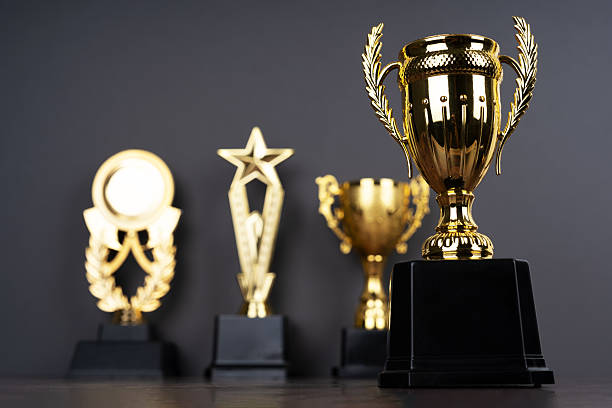 istock Standing golden trophy cups on dark grey background. One trophy is focused 2206391754