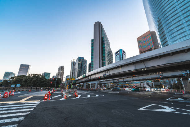 Cars driving on a wide avenue with skyscrapers and an elevated highway in tokyo, japan, during a clear afternoon