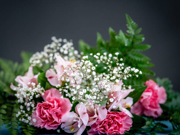 Dried flowers in soft green and pastel colors arranged on a dark surface with shallow depth of field. Conceptual image representing calm, simplicity, beauty, nature, wellness, and minimalist design with copy space.