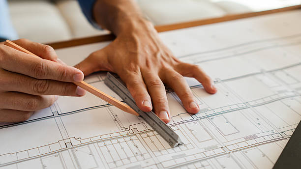 istock Architect drawing lines on a blueprint using a ruler and pencil 2206402932