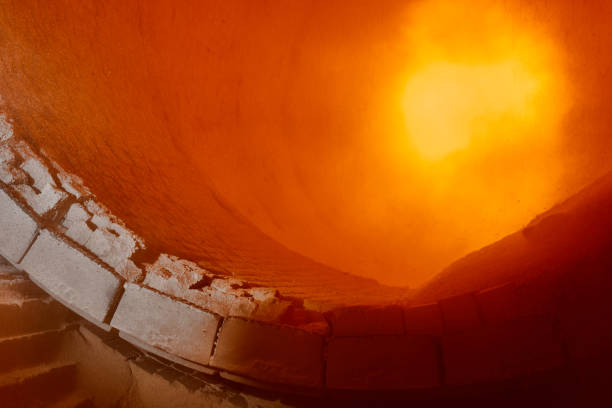 Working area of rotating calcium carbonate burning kiln with orange flame in workshop closeup. Lime and cement plant. Heat processing