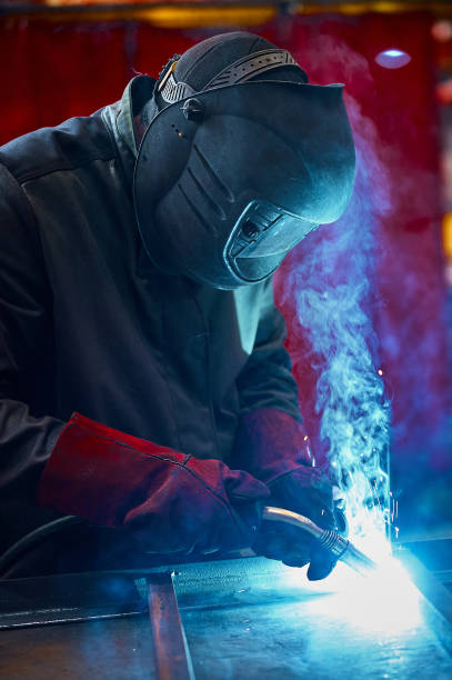 istock Laborer in protective mask welds manually metal frame 2206406101