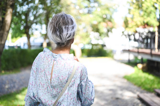 istock Senior woman walking away in a peaceful park setting 2206408600