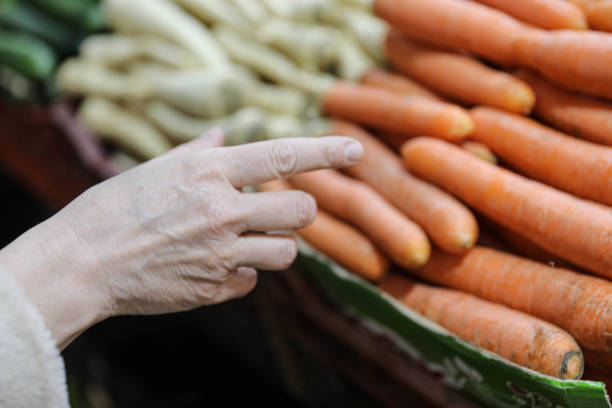 Elderly Lady Selecting Fruits and Vegetables at a Market Stall – A Concept of Healthy Living and Nutrition