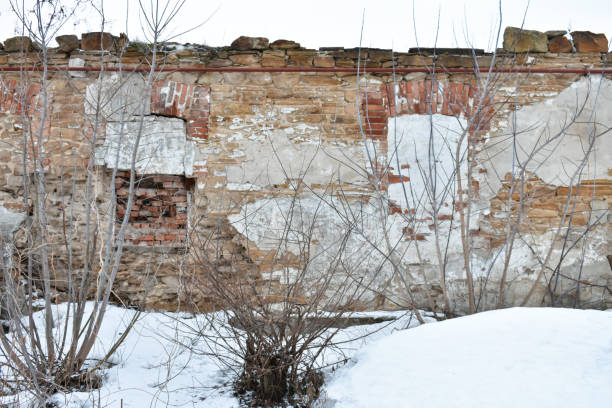 istock Imposing brick and stone wall surrounded by bare trees with snowy foreground 2206409154