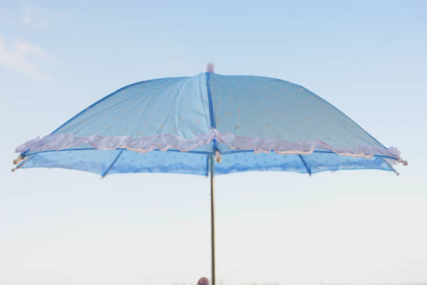 A chic blue umbrella with a ruffled edge stands out against a vibrant, bright sky