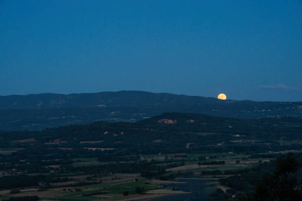Moon rising in night sky above the agricultural valley outside the village of Gordes, Provence,  France
