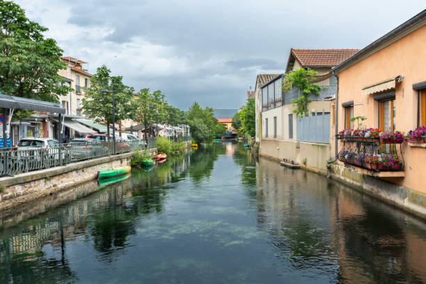 Pretty canal lined with plants, kayaks and trees on a cloudy day, Isle sur la Sorgue, Provence, France, Europe