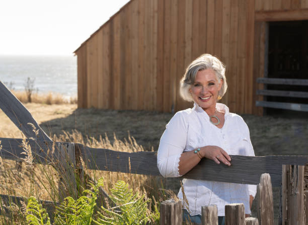 Middle age woman posing outdoors by barn. Professional model.