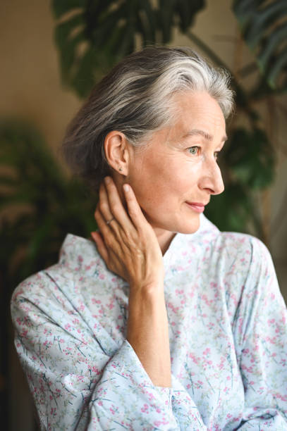 Senior woman gently touching her neck while looking away