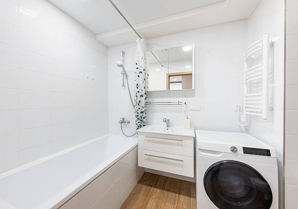 istock Modern Home White Bathroom With Bathtub, Washer, and Mirrored Cabinet 2206412037