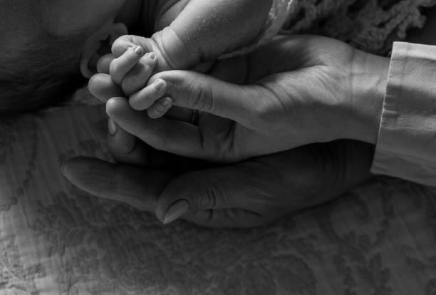 istock Newborn's small hand gently holds mother's tender finger close-up 2206412954