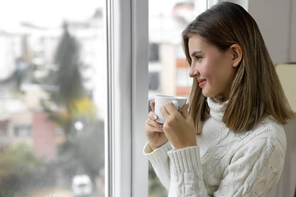 istock Beautiful woman looking through window in a contented emotion 2206413769