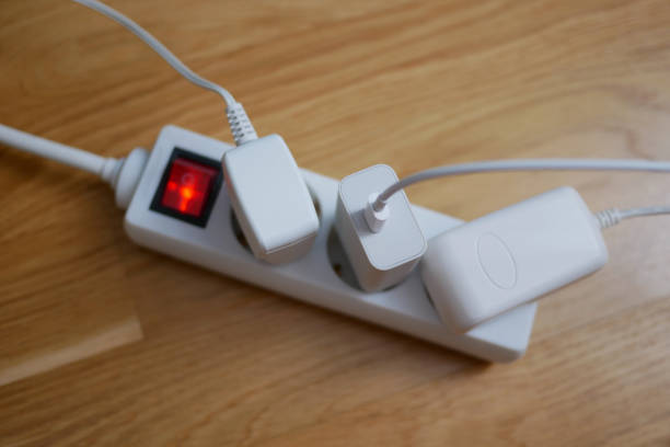 Three electric cables are plugged into a power strip socket extension cord.