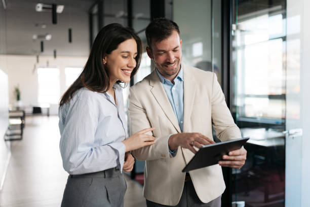 istock Smiling business people using digital tablet in office corridor 2206419140