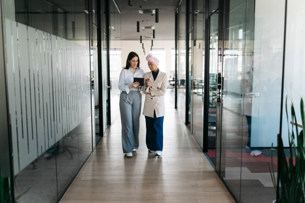 istock Two businesswomen walking and talking in modern office corridor 2206419406