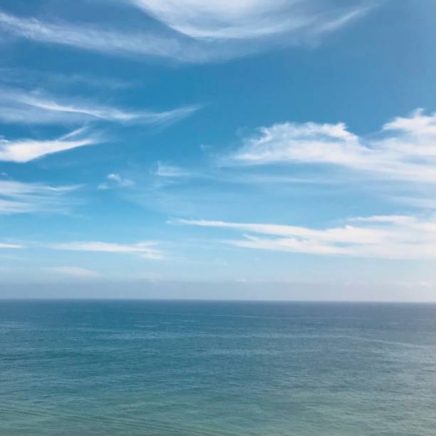istock A serene seascape vast expanse ocean blends harmoniously into a bright horizon blue sky airy wispy cirrus clouds scattered above. 2206423452