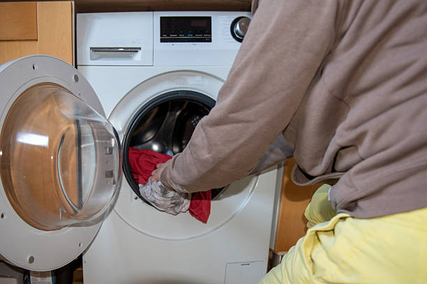 Person doing laundry, loading clothes into washing machine. stock photo