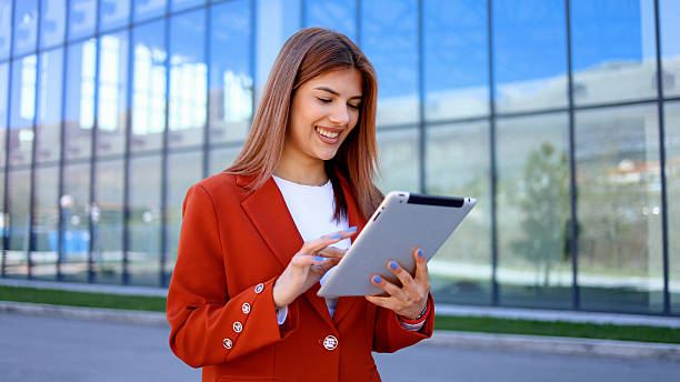 istock Smiling businesswoman using digital tablet in front of modern office building 2206426271