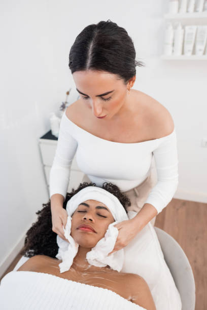istock Beautician cleaning face of client lying on massage table 2206426465