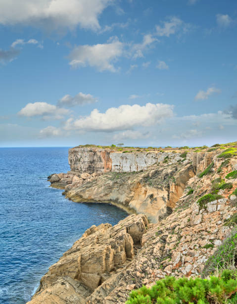 Majestic cliffs of Mallorca cascade into the shimmering blue sea under a stunning sky in Spain.