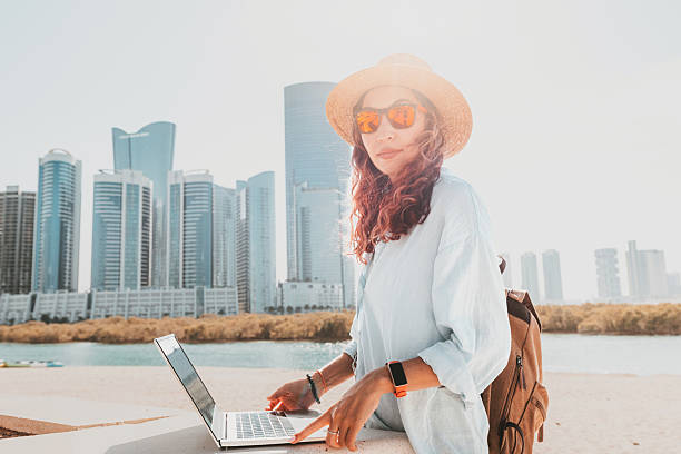 istock Freelancer working on a laptop while soaking in the stunning views of modern skyscrapers in Abu Dhabi's vibrant skyline 2206439085