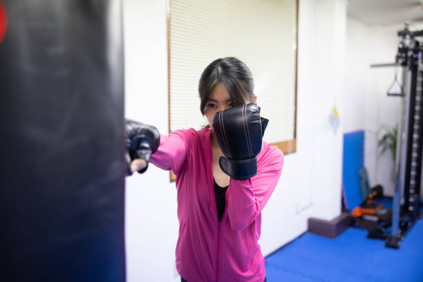 istock Female athlete training boxing in gym - punching sandbag 2206439224