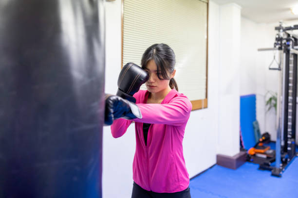 istock Female athlete training boxing in gym - punching sandbag 2206439384