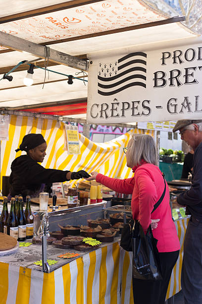 Paris, France: A retail transaction at a crepe stall at the outdoor weekly Bastille market in the 11th arrondissement; the vendor hands change to a customer.