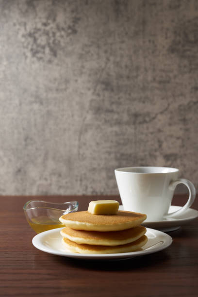drizzled with honey, a large number of delicious pancakes stacked together on a white bowl, a tower of small milk pancakes on a ceramic bowl with bee honey, close up, side view