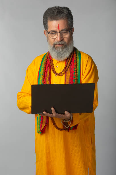istock Senior priest with laptop standing on white background 2206465373
