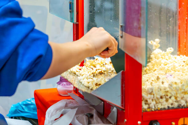 istock putting popcorn on a plate. machine for making and heating popcorn. woman putting popcorn on. 2206465707