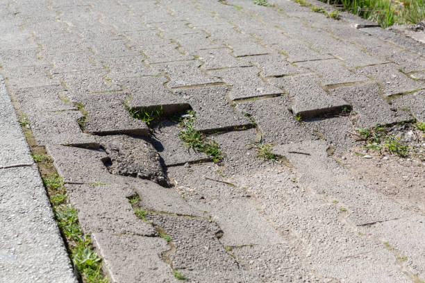 istock Damaged pavement with overgrown grass highlighting urban maintenance and repair needs 2206466143