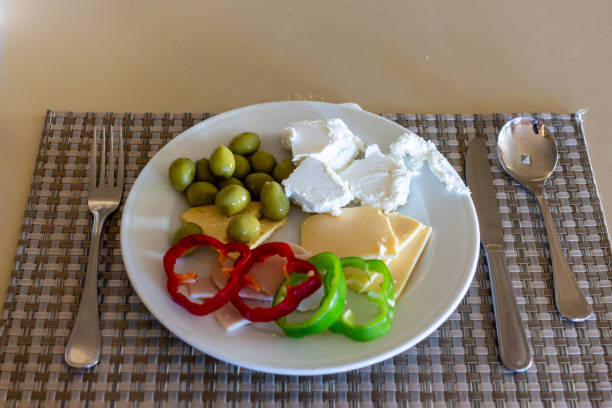 Fresh Mediterranean appetizer plate with olives, cheese, and bell peppers on woven placemat setting