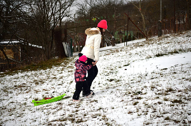 Family on the winter vacation sledding downhill