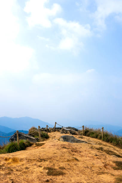 rocky mountain trail viewpoint at phu chi fa with safety ropes, blue sky, scenic cliffs, and misty hills in northern thailand