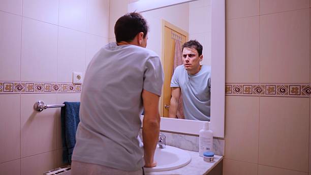 istock Sleepy man looking at his reflection in the bathroom mirror on monday morning 2206470067