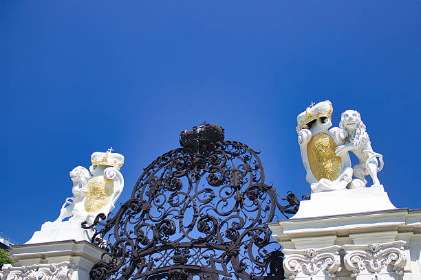 June 3, 2019 - Vienna, Austria - Decorative wrought iron gate topped with golden crowned lions at the entrance to Belvedere Palace.