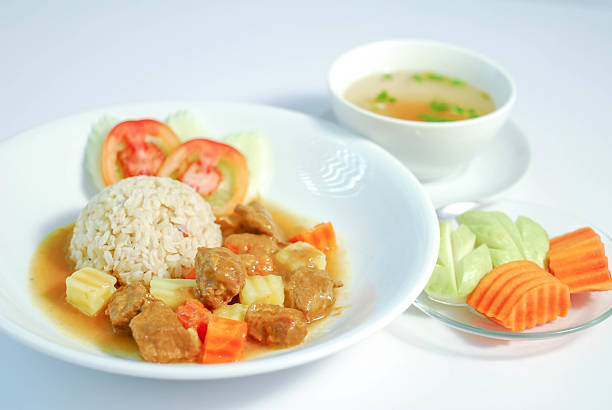 Pork sirloin stew, A delicious Thai pork stew with rice, served with clear soup and fresh vegetables on a white background, healthy homemade meal concept, Thaifood
