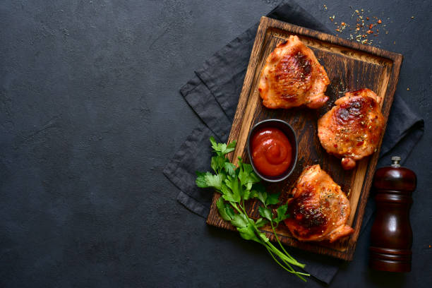 istock Roasted chicken thighs with ketchup on a rustic wooden board. Top view with copy space. 2206478534