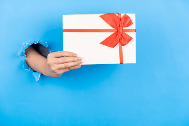 istock Female hand holding a gift card through a paper background 2206486742
