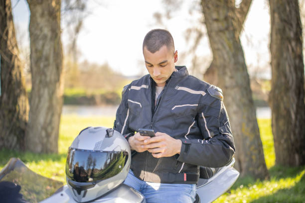 istock Handsome biker taking a break on motorbike near the river while using smart phone. 2206492083