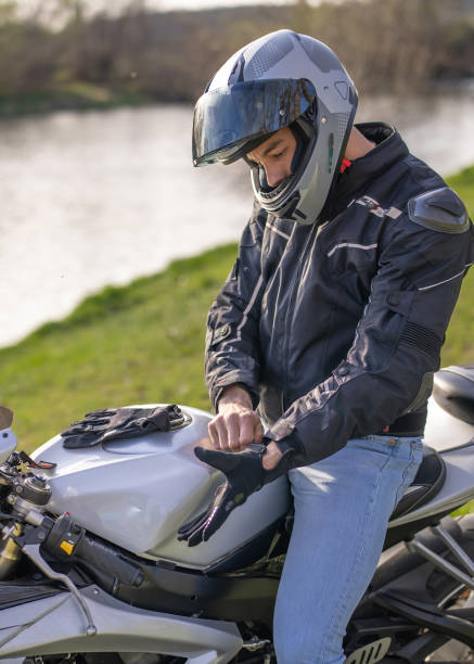 istock Handsome men getting ready to ride a motorcycle and wearing gloves while sitting on his sport motorcycle near the river 2206492916