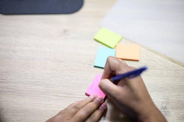 Hospital administrator writing on sticky notes and using laminator in office
