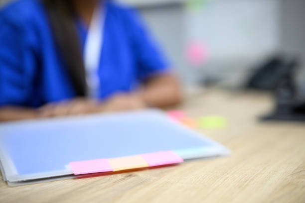 Hospital administrator writing on sticky notes and using laminator in office