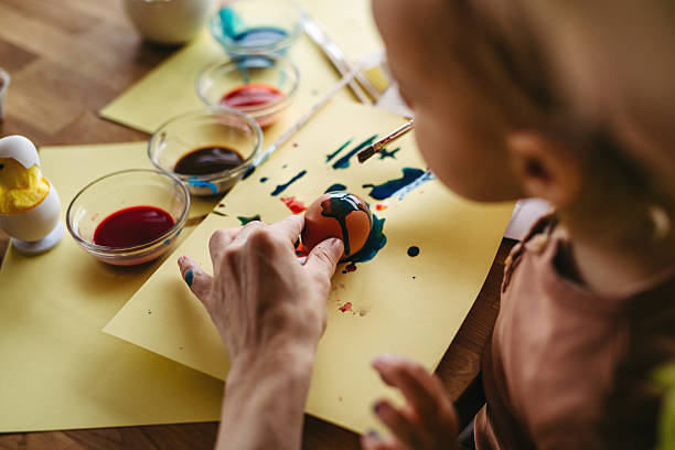 istock Close up of little boy decorating easter eggs at home. 2206496015