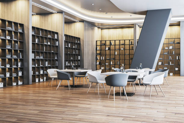Stylish library with wooden bookshelves, modern chairs, and tables in a well-lit space. Contemporary design with warm lighting and wood flooring. 3D Rendering