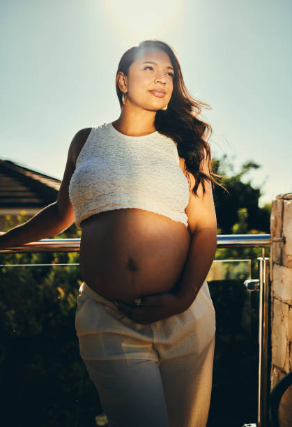 istock Pregnant Woman Standing on Sunny Balcony 2206504697